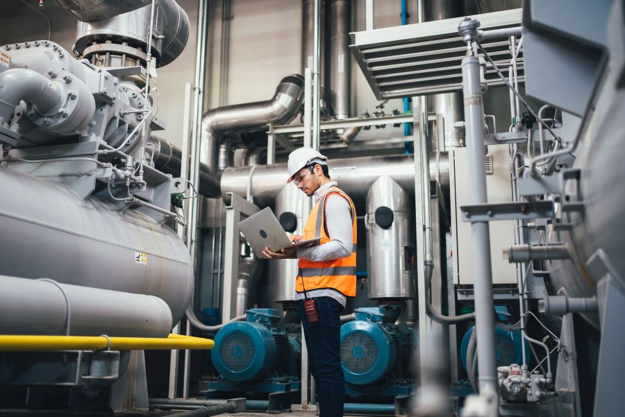 Professional worker of modern factory using laptop controlling p